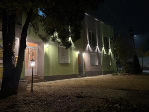 a green building with a street light next to a tree at Vila Alexandra 2025 in Bačka Topola