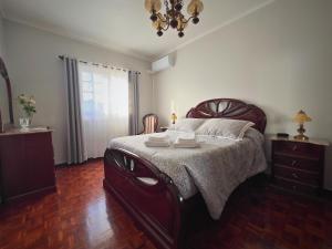 a bedroom with a large bed and a chandelier at A Casa do Navio in Capelas