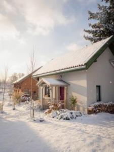 a house with snow on the ground in front of it at Po Prostu Dobro in Mrągowo