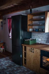 a kitchen with a black refrigerator and wooden cabinets at Chata Svahovka in Malá Morávka +32 photos