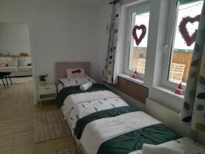 two beds in a room with two windows at Biela Magnólia in Vrbov