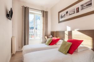 two beds in a hotel room with a window at Hôtel d'Ossau in Laruns +20 photos