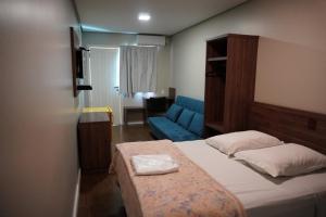 a bedroom with a bed and a blue couch at Hotel Ponto 1 in Vacaria +11 photos
