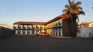 a building with a car parked in a parking lot at Hotel Ponto 1 in Vacaria