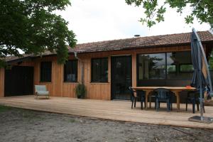 a house with a wooden deck with a table and chairs at Maison Claouey in Lège-Cap-Ferret