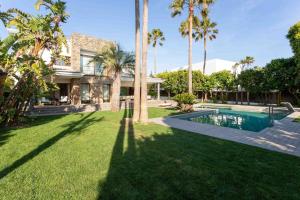 a house with a yard with a swimming pool and palm trees at A paradise with ocean views in Conil de la Frontera