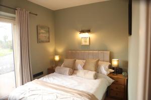 a bedroom with a bed with white sheets and pillows at Cuilcagh Luxury Studio in Enniskillen