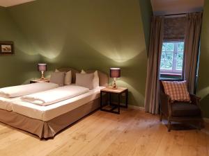 a bedroom with a bed and a chair and a window at Gut Altholz Landhotel und Restaurant Hutter in Plattling