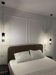 a bedroom with a white bed with two lights above it at Apartament 2 camere Fial in Bacău