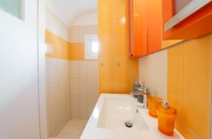 a bathroom with a white sink and orange cabinets at Coastal Escape - 2 min from Perissa Beach in Perissa +60 photos