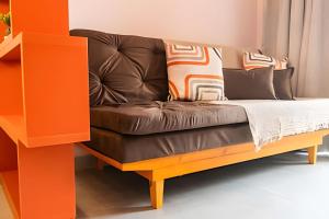 a brown couch in a living room with an orange shelf at Modernidade no Coração de Cuiabá in Cuiabá