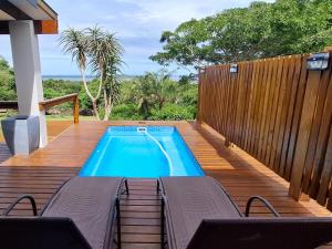 a swimming pool on a wooden deck with two chairs at The Lake House in Hluhluwe