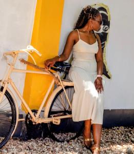 a woman in a white dress sitting on a bike at Mwana House in Nungwi