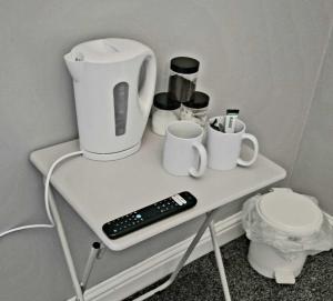 a table with a coffee pot and cups and a remote control at Cog Lane House in Burnley