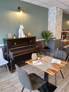 a piano in a restaurant with a table and chairs at Chez Les Papa's in Aspres-sur-Buëch