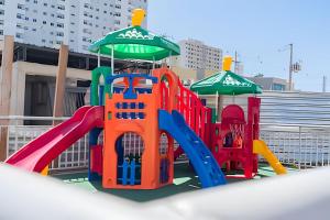 a playground with a slide and umbrellas at Seu Refúgio em Cuiabá in Cuiabá