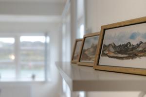 two framed paintings on a shelf in a room with a window at Sallinnguit in Sisimiut +24 photos
