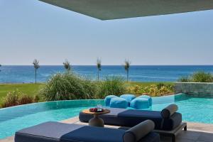 a swimming pool with blue furniture and the ocean at Atlantica Dreams Resort in Gennadi