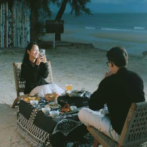 a woman taking a picture of a woman sitting at a table with food at Tropical eglamping Mũi Né in Ấp Long Sơn