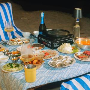a table with plates of food and a bottle of wine at Tropical eglamping Mũi Né in Ấp Long Sơn