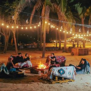 a group of people sitting around a fire on the beach at Tropical eglamping Mũi Né in Ấp Long Sơn