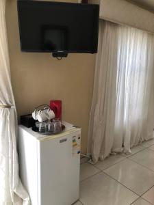 a television on the wall above a small refrigerator at Kamogelo Guest House in Pilanesberg