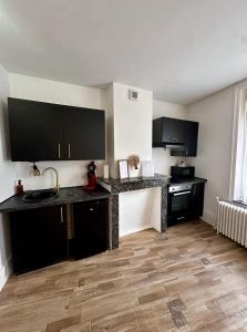 a kitchen with black cabinets and a counter top at Studio 2 des Remparts à 5mins de Charleville-Mézières in Warcq