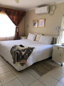 a bedroom with a large bed with a white comforter at Kamogelo Guest House in Pilanesberg +53 photos