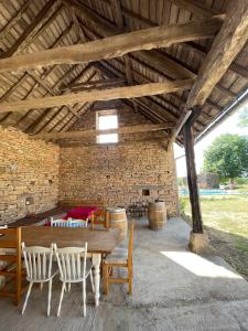 a room with a table and chairs and a brick wall at Auberge des Riders in Loze