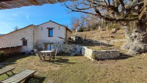 a stone house with a table and chairs in a yard at Chambre de la roche trouee GR49 in Trigance