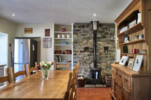 a kitchen with a wooden table and a stone fireplace at Glenalbyn Cottage in Saint Fillans