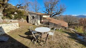 a table and chairs in front of a house at Chambre de la roche trouee GR49 in Trigance