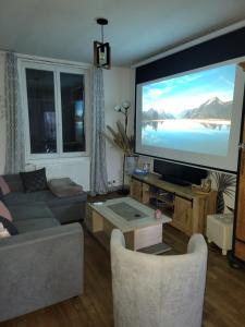 a living room with a large flat screen tv at Gite piscine privée climatisation in Célon
