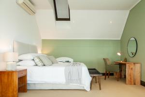 a bedroom with a bed and a table and a mirror at Manor at Longridge in Helderberg +35 photos