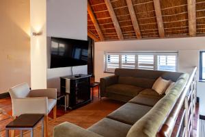 a living room with a couch and a tv at Manor at Longridge in Helderberg