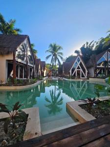 ein Swimmingpool in einem Ferienresort mit Häusern und Palmen in der Unterkunft Kaaj Ndomi in Bacalar