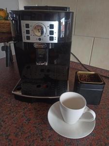 a cup of coffee on a plate next to a coffee maker at Apartmán Vendelínka in Valtice