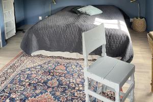 a white chair sitting in front of a bed at Villa Vitviken Sleeps 4 with Pool in Slite +29 photos
