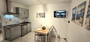 a kitchen with a table and a television on the wall at Le Duplex t2 étoilé in Saint-Méloir-des-Ondes