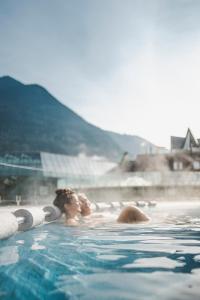 a couple of people in a swimming pool at FERIENHAUS BERGBLICK 10-25 PERS Urig, echt & perfekt für Familien und Freunde Ideal für unvergessliche Tage mit traumhaftem Bergpanorama in Längenfeld
