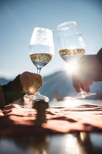 two people holding glasses of wine on a table at FERIENHAUS BERGBLICK 10-25 PERS Urig, echt & perfekt für Familien und Freunde Ideal für unvergessliche Tage mit traumhaftem Bergpanorama in Längenfeld