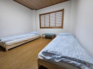 two beds in a room with a window at Kobe Youth Hostel in Kobe