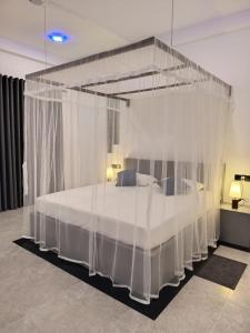 a bedroom with a canopy bed with white curtains at The BLISS Mihiripenna in Talpe
