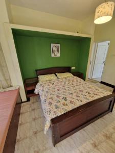 a bedroom with a bed with a green wall at Narmada Holiday Home in Ooty