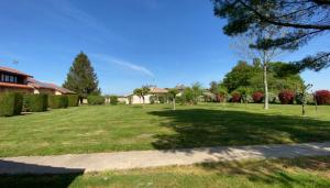 a large grassy yard with trees and houses at Les Genêts Studio & Piscine in Eugénie-les-Bains