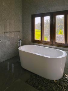 a white bath tub in a bathroom with a window at Wa'a House Batukaras in Batukaras +62 photos