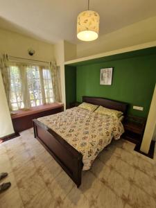 a bedroom with a bed with a green wall at Narmada Holiday Home in Ooty