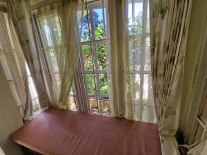 a large window with a wooden bench in front of it at Narmada Holiday Home in Ooty