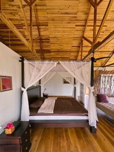 a bed in a room with a wooden ceiling at Wa'a House Batukaras in Batukaras