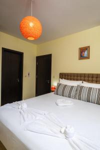 a bedroom with a large white bed with an orange light at Апартамент Боров рай in Velingrad +16 photos